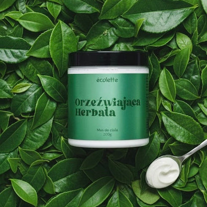 Wegański mus do ciała Orzeźwiająca Herbata Écolette w aranżacji z liśćmi herbaty podkreślającymi świeży zapach.