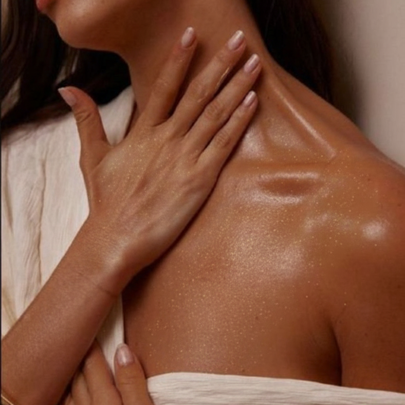 Kobieta z rozświetloną skórą po użyciu wegańskiego musu do ciała Złoty Dotyk Écolette z 24-karatowym złotem.